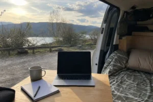 Ordinateur, carnet et tasse dans un van ouvert sur un paysage naturel